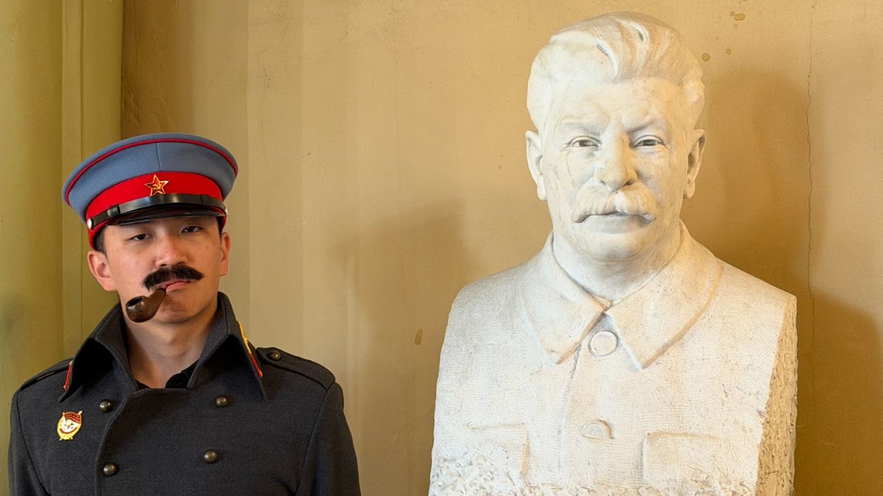 In period costume beside a Stalin bust while filming in Tbilisi